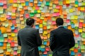 Businessmen collaborating in front of a wall of sticky notes representing brainstorming ideas Royalty Free Stock Photo