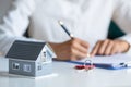 Businessmen and customers are signing home purchase agreements. Hand holding the pen signing purchase contract. Gray roof houses Royalty Free Stock Photo