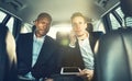 Businessmen driving to work in the backseat of a car