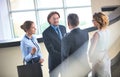 Businessmen greeting while standing with colleagues at reception lobby in office