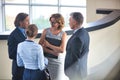 Businessmen greeting while standing with colleagues at reception lobby in office