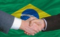 Businessmen handshake in front of brazil flag