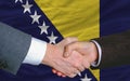 businessmen handshake after good deal in front of bosnia herzegovina flag