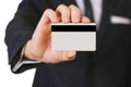 Businessmen holding credit card proposing it to you. Hand in black suit holds out a blank grey credit card. Close up. Royalty Free Stock Photo