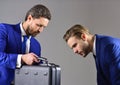 Businessmen look into opened black briefcase on dark background.