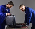 Businessmen look into opened briefcase on dark background.