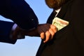 Businessmen make bargain. Male hand puts cash into suit pocket