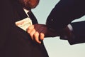 Businessmen make bargain. Male hand puts cash into suit pocket