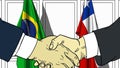Businessmen or politicians shake hands against flags of Brazil and Chile. Official meeting or cooperation related