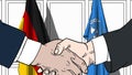 Businessmen or politicians shake hands against flags of Germany and United Nations. Official meeting or cooperation