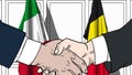 Businessmen or politicians shake hands against flags of Italy and Belgium. Official meeting or cooperation related