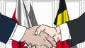 Businessmen or politicians shake hands against flags of Poland and Belgium. Official meeting or cooperation related