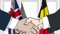 Businessmen or politicians shake hands against flags of Britain and Belgium. Official meeting or cooperation related