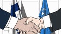 Businessmen or politicians shake hands against flags of Finland and United Nations. Official meeting or cooperation