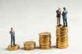 Businessmen shake hands as a symbol of a successful profitable transaction. Businessmen on a stack of gold coins with steps as a