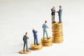 Businessmen shake hands as a symbol of a successful profitable transaction. Businessmen on a stack of gold coins with steps as a