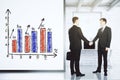 Businessmen shake hands in loft office with white wall with business graph