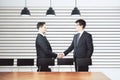Businessmen shake hands in modern conference room with furniture Royalty Free Stock Photo