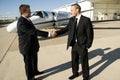 Businessmen shaking hands in front of corporate je Royalty Free Stock Photo