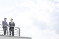 Businessmen standing at terrace railings against cloudy sky