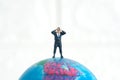 Businessmen standing using binoculars above earth globe. Miniature tiny people toys photography.  on white background Royalty Free Stock Photo