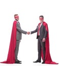 Businessmen in superhero capes, shaking hands with each other