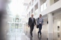 Businessmen Talking As They Walk Through Office Lobby