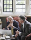 Businessmen Talking Over Laptop In Lobby