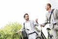 Businessmen talking while walking with bicycles outdoors
