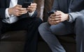 Businessmen using mobile phones sitting on couch