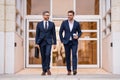 Businessmen walk in the street. Two businessmen walking and talking at office building. Two american businessmen in Royalty Free Stock Photo