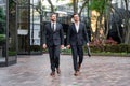 Businessmen walk in the street. Two businessmen walking and talking at office building. Two american businessmen in Royalty Free Stock Photo