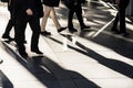 Businessmen walking fast on city sidewalk silhouetted in bright sunlight, one man stands out wearing light pants, different Royalty Free Stock Photo