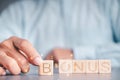 Businessmen wear a white shirt at their desks in the office. Use your hand to pick up a wooden cube inscribed with the word bonus