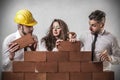 Businessmen and woman building a wall