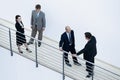 Businessmen and woman standing together by railing and conversing