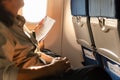 Businessn woman seat next to window on airpane holding paper work on journey vacation.