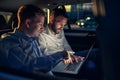 Businesspeople in car working on laptop in back seat Royalty Free Stock Photo