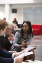 Businesspeople Discuss Document In Lobby Of Modern Office