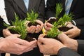 Businesspeople hands with plant and soil