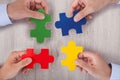 Businesspeople joining multicolored puzzle pieces at desk