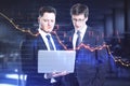 Businesspeople looking in laptop and glowing falling forex chart