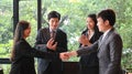 Businesspeople are making confidence in others with handshakes while standing in the meeting room.