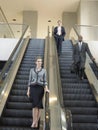 Businesspeople Moving Down On Escalator In Office