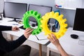 Businesspeople`s Hand Joining Green And Yellow Gears Royalty Free Stock Photo