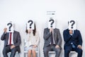 Businesspeople sitting in queue and waiting for interview, holding question marks in office Royalty Free Stock Photo