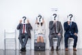 Businesspeople sitting in queue and waiting for interview, holding question marks in office Royalty Free Stock Photo