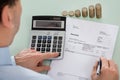 Businessperson Calculating Invoice With Coins At Desk Royalty Free Stock Photo