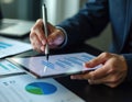Businessperson examines tax return details on digital tablet. Consultant uses digital pen to highlight data points on chart.