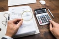 Businessperson Examining Bills With Magnifying Glass Royalty Free Stock Photo